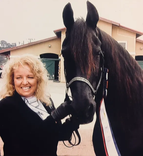 Jackie Barikhan with a black horse wearing show ribbons